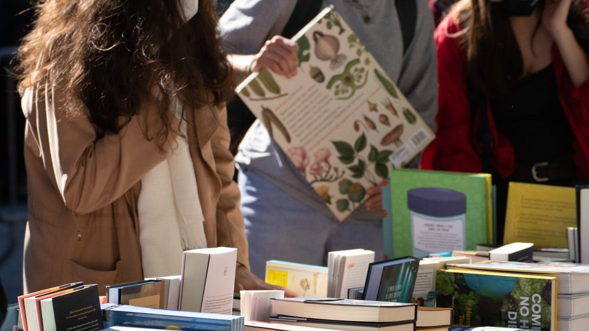 Besucher st&ouml;bern an einem Stand mit ausgelegten B&uuml;chern